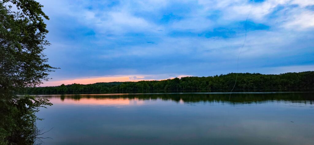 Evening on the Tennessee River at Blue Heron — calm water reflecting a pink afterglow under a blue evening sky
